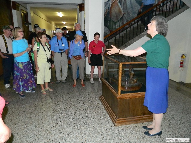 Dr. Caldwell describing a bronze statue of native people in building lobby